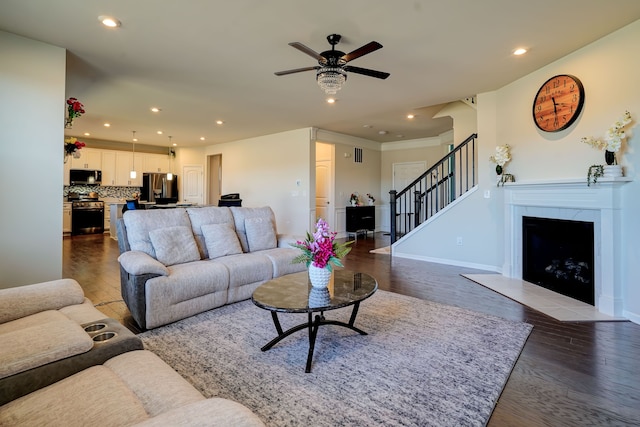 living room featuring baseboards, stairs, recessed lighting, a fireplace, and wood finished floors