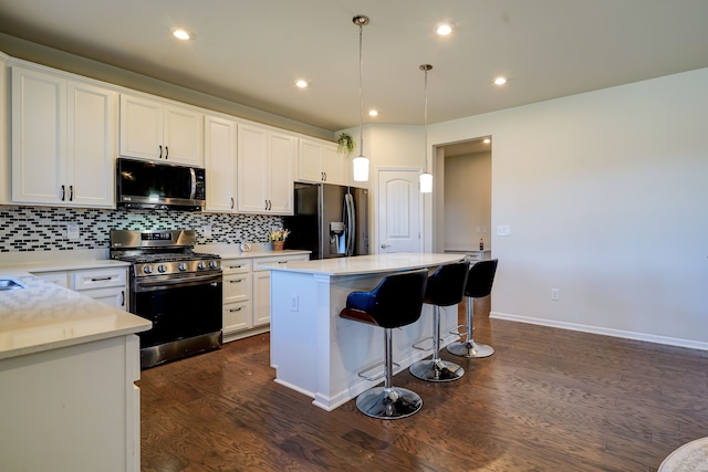 kitchen with tasteful backsplash, light countertops, stainless steel appliances, white cabinetry, and dark wood-style flooring