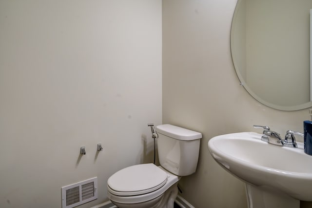 bathroom featuring a sink, visible vents, baseboards, and toilet