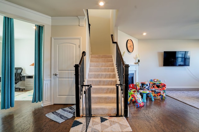 staircase featuring a fireplace, crown molding, recessed lighting, and wood finished floors