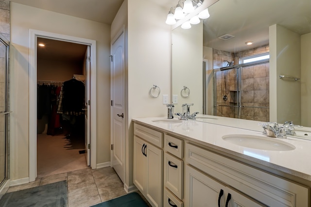 full bath with a sink, a stall shower, double vanity, and tile patterned floors