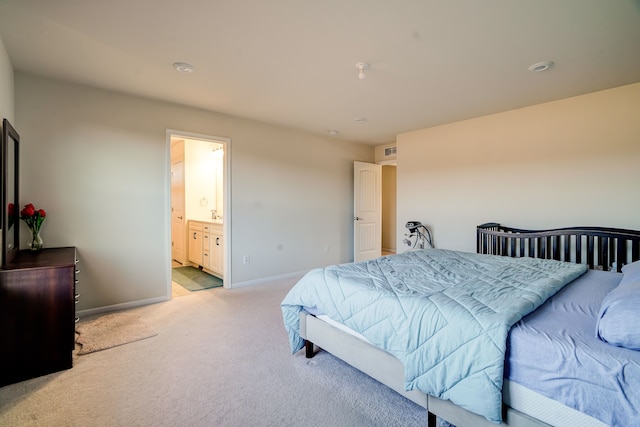 bedroom with light carpet, ensuite bath, and baseboards