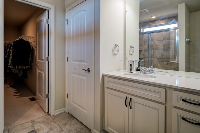 full bath with tile patterned floors, visible vents, a walk in closet, a shower stall, and vanity