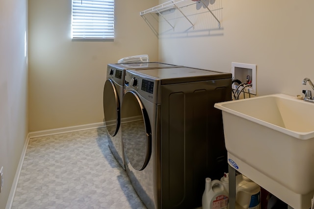 washroom featuring laundry area, baseboards, independent washer and dryer, and a sink