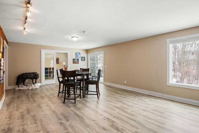 dining area with light wood-style floors, track lighting, and baseboards