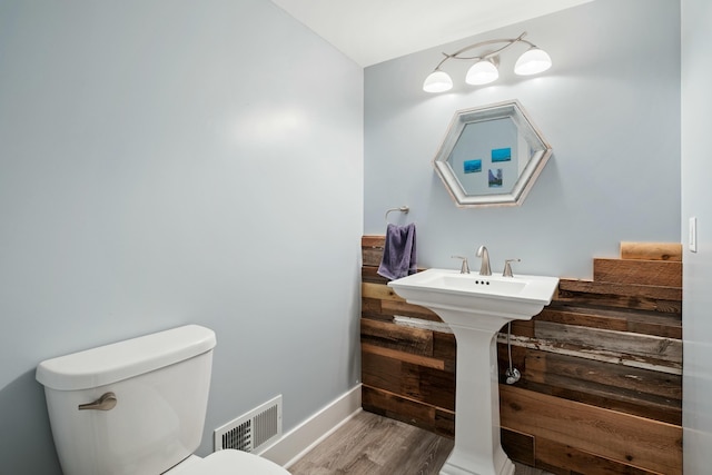 bathroom featuring toilet, baseboards, visible vents, and wood finished floors