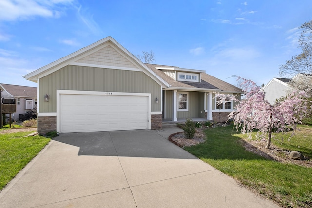 view of front of property with covered porch, concrete driveway, a front yard, and stone siding