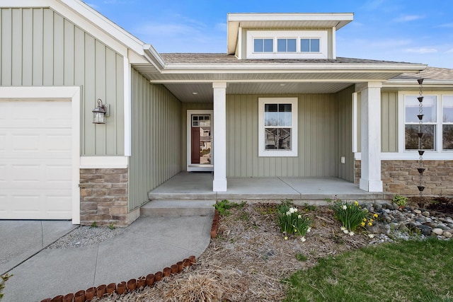 doorway to property featuring covered porch, board and batten siding, roof with shingles, a garage, and stone siding
