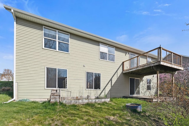 back of property with a lawn, a fire pit, and a deck