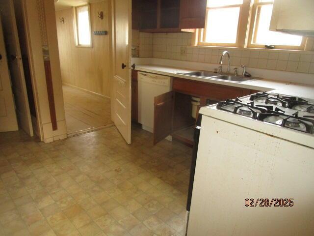 kitchen featuring white appliances, decorative backsplash, light countertops, light floors, and a sink