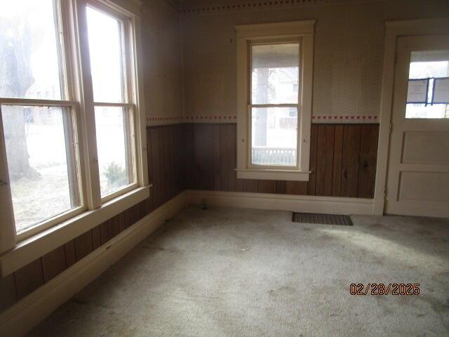 unfurnished room featuring carpet floors, wood walls, and visible vents