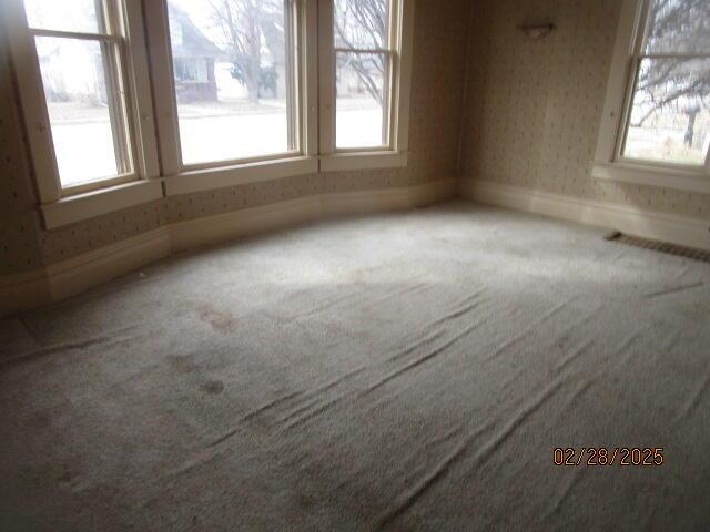 spare room featuring baseboards, carpet, and wallpapered walls