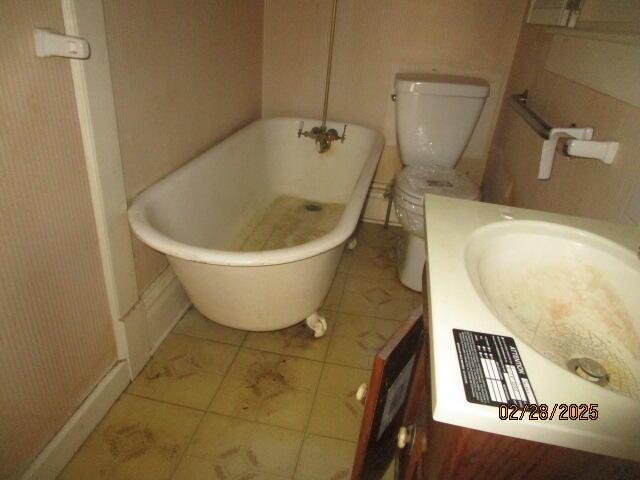 full bath featuring a soaking tub, vanity, and toilet