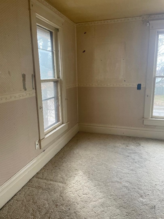 unfurnished room with light colored carpet, baseboards, and wallpapered walls