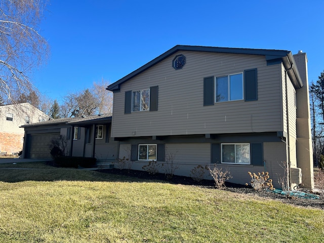 tri-level home featuring a front lawn, a chimney, an attached garage, and brick siding