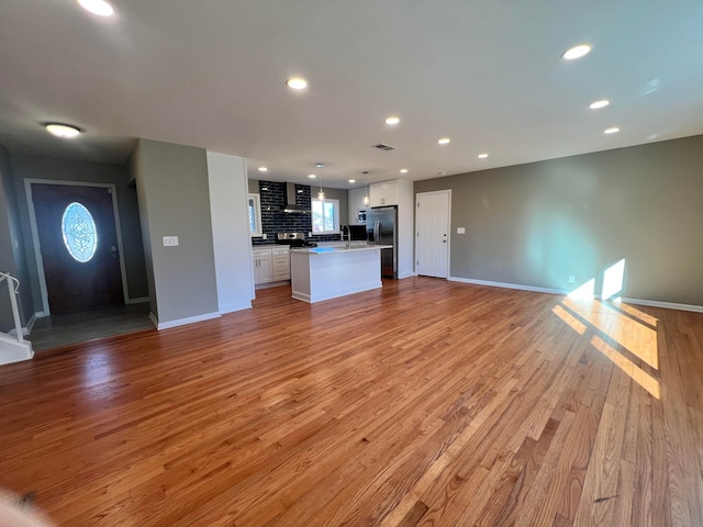 unfurnished living room featuring light wood-style flooring, visible vents, baseboards, and recessed lighting