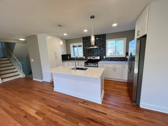 kitchen featuring wall chimney exhaust hood, decorative backsplash, stainless steel appliances, and a sink