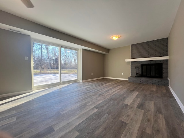 unfurnished living room featuring baseboards, a fireplace, visible vents, and dark wood finished floors