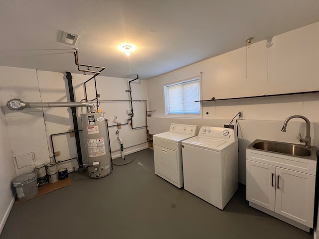 clothes washing area with washing machine and clothes dryer, gas water heater, a sink, and cabinet space