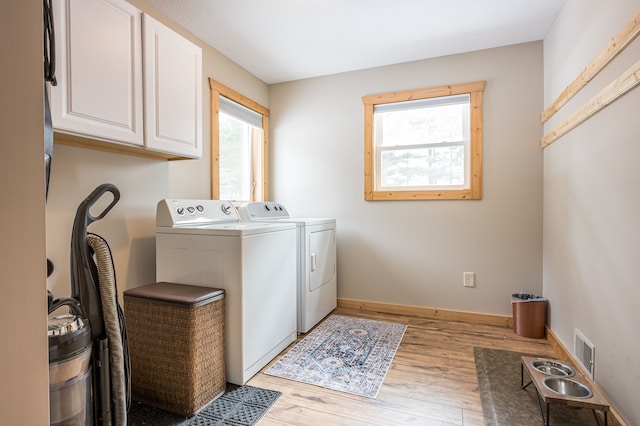 laundry area with visible vents, independent washer and dryer, wood finished floors, cabinet space, and baseboards