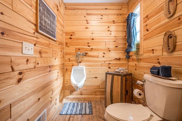 bathroom with toilet, wood finished floors, and wood walls