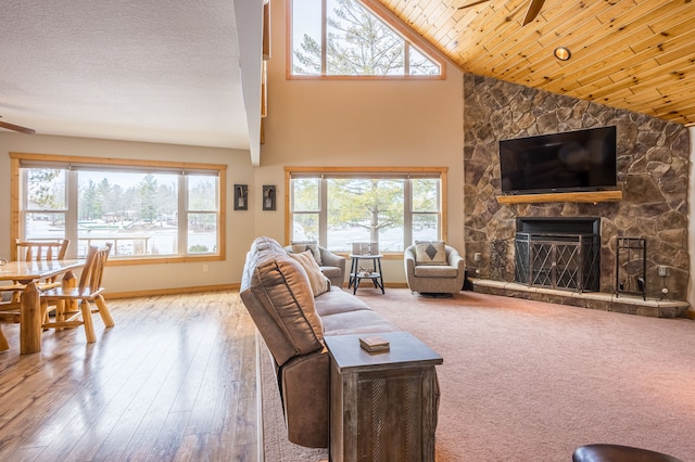 living area with a fireplace, wood ceiling, a ceiling fan, and a textured ceiling