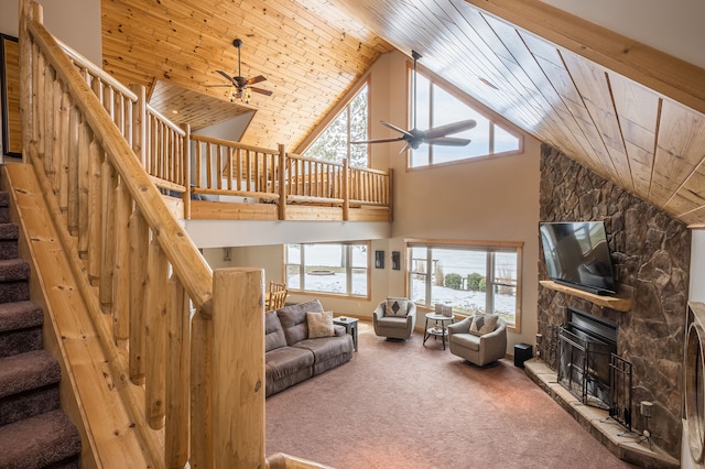 carpeted living room with ceiling fan, stairway, wood ceiling, a fireplace, and high vaulted ceiling