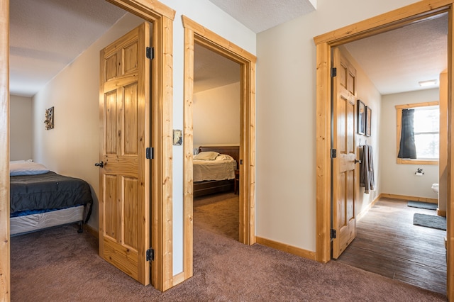 hall featuring baseboards, carpet floors, and a textured ceiling