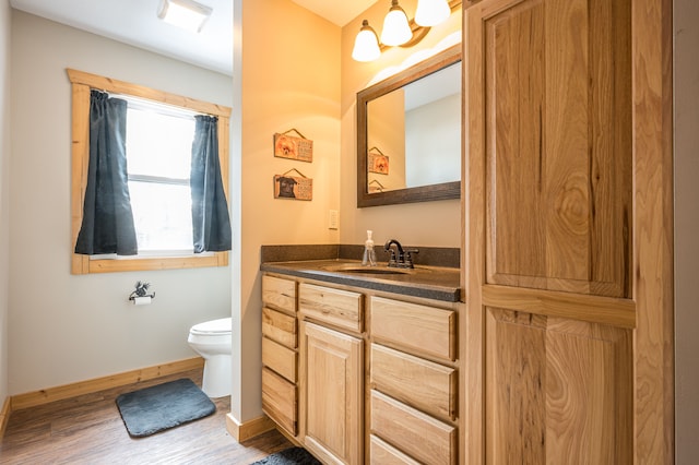 bathroom with baseboards, toilet, wood finished floors, and vanity