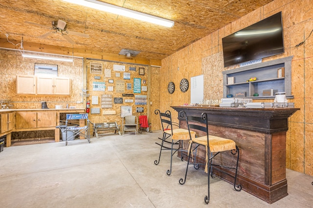 bar with ceiling fan, concrete flooring, and a dry bar