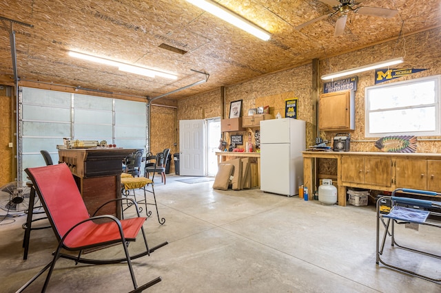 garage featuring a workshop area, freestanding refrigerator, and a ceiling fan