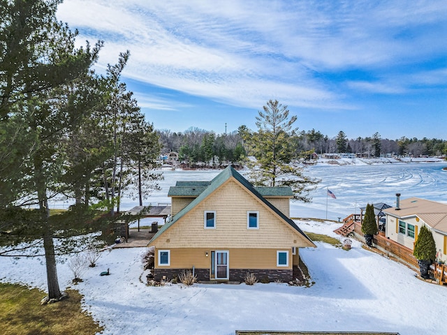 snow covered property with stone siding