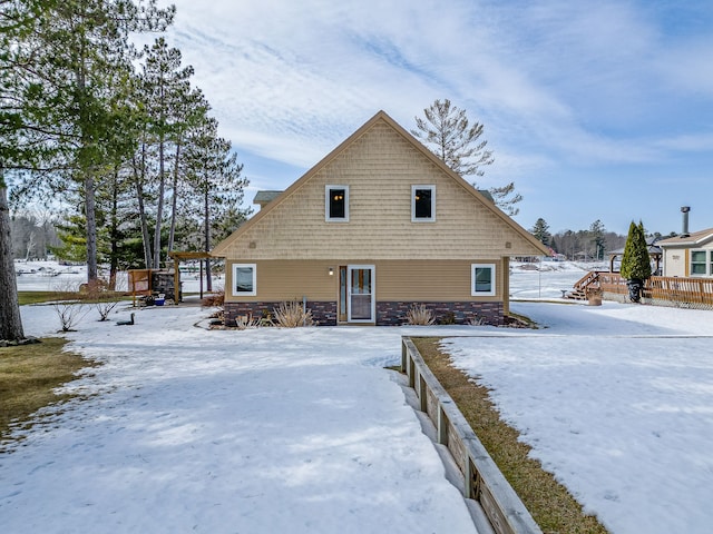 snow covered property with stone siding