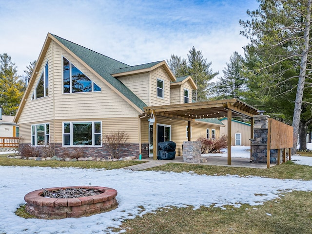 snow covered back of property with stone siding