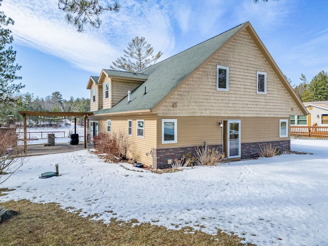 snow covered house featuring a shingled roof