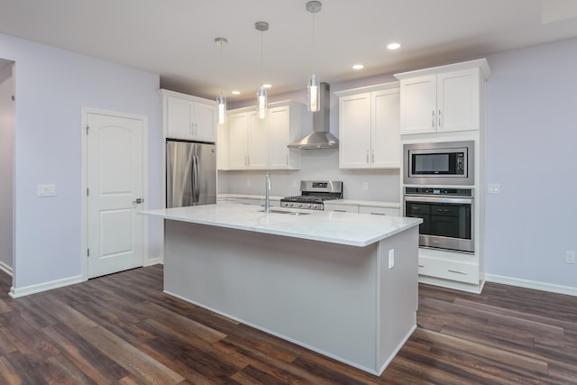 kitchen featuring a center island with sink, dark wood-style floors, wall chimney exhaust hood, appliances with stainless steel finishes, and a sink