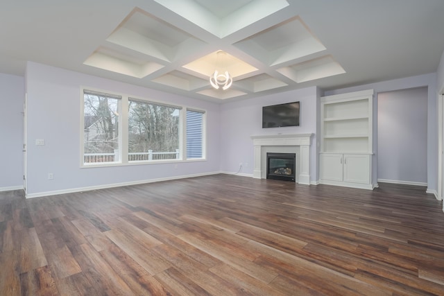 unfurnished living room featuring a glass covered fireplace, coffered ceiling, dark wood finished floors, and baseboards