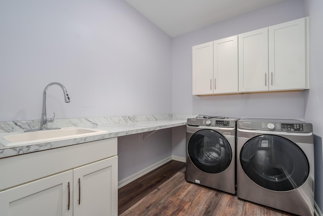 washroom with cabinet space, washing machine and dryer, dark wood-style floors, and a sink