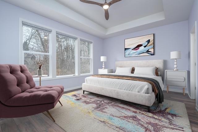 bedroom with a ceiling fan, a raised ceiling, baseboards, and wood finished floors