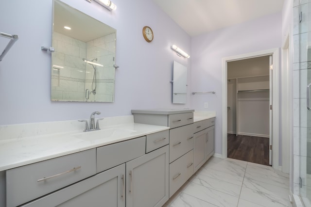 full bathroom featuring marble finish floor, a shower stall, vanity, and a spacious closet