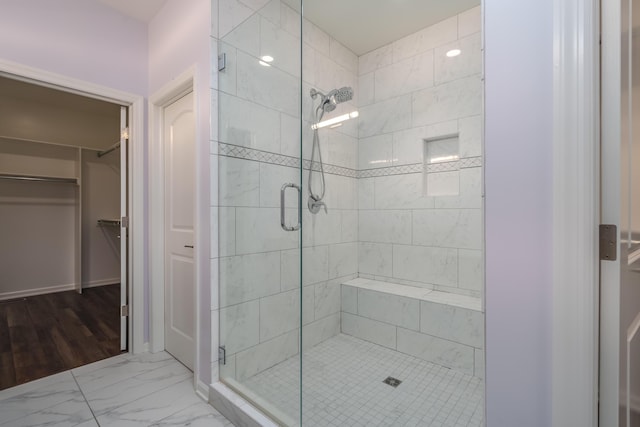 full bathroom with marble finish floor, a shower stall, and a walk in closet