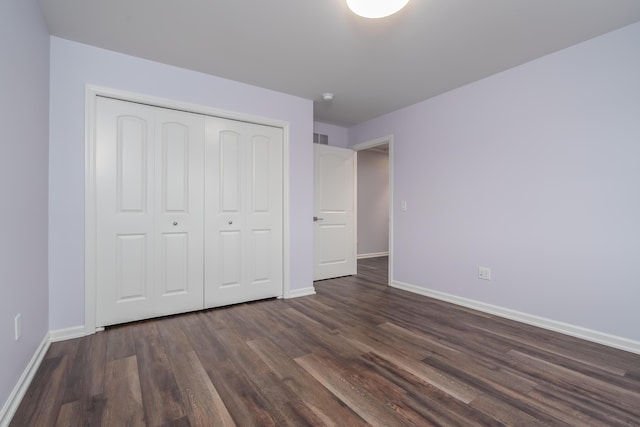 unfurnished bedroom featuring dark wood-style floors, visible vents, baseboards, and a closet