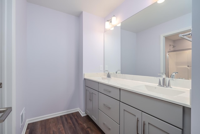 bathroom featuring baseboards, a shower, a sink, and wood finished floors