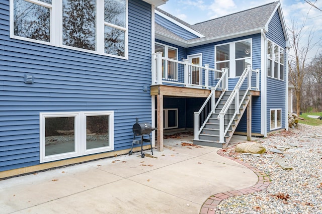 back of house with a patio area, roof with shingles, and stairs