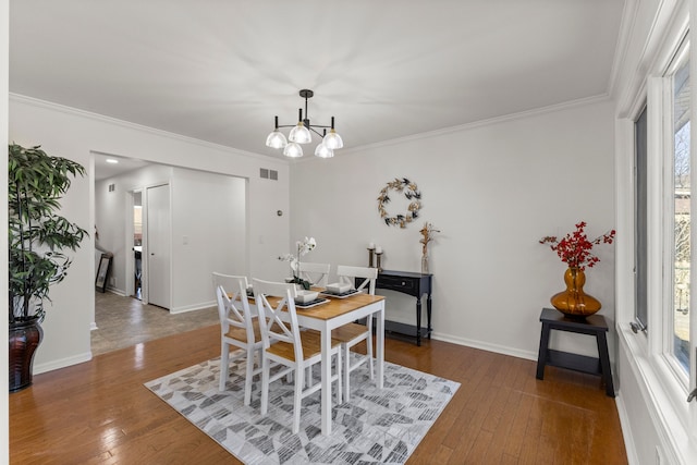 dining area with a notable chandelier, crown molding, visible vents, and hardwood / wood-style floors