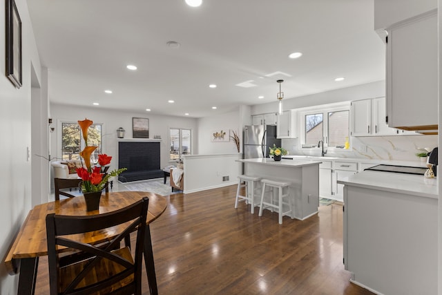 kitchen with dark wood-style floors, a fireplace, freestanding refrigerator, range, and a center island