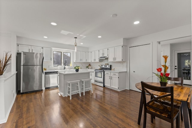 kitchen with appliances with stainless steel finishes, dark wood finished floors, white cabinets, and light countertops