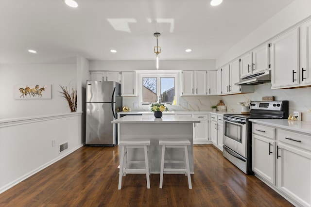 kitchen featuring under cabinet range hood, white cabinets, appliances with stainless steel finishes, and dark wood-type flooring