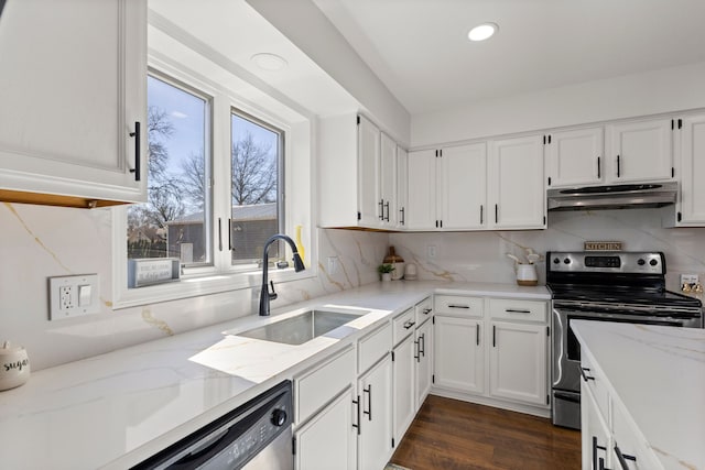 kitchen with under cabinet range hood, a sink, tasteful backsplash, white cabinetry, and appliances with stainless steel finishes