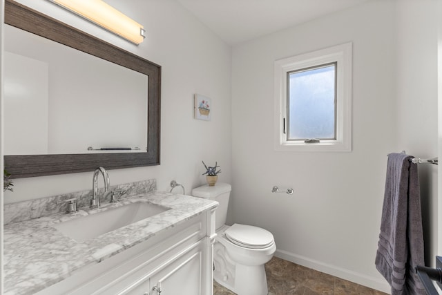 half bath featuring baseboards, toilet, and vanity